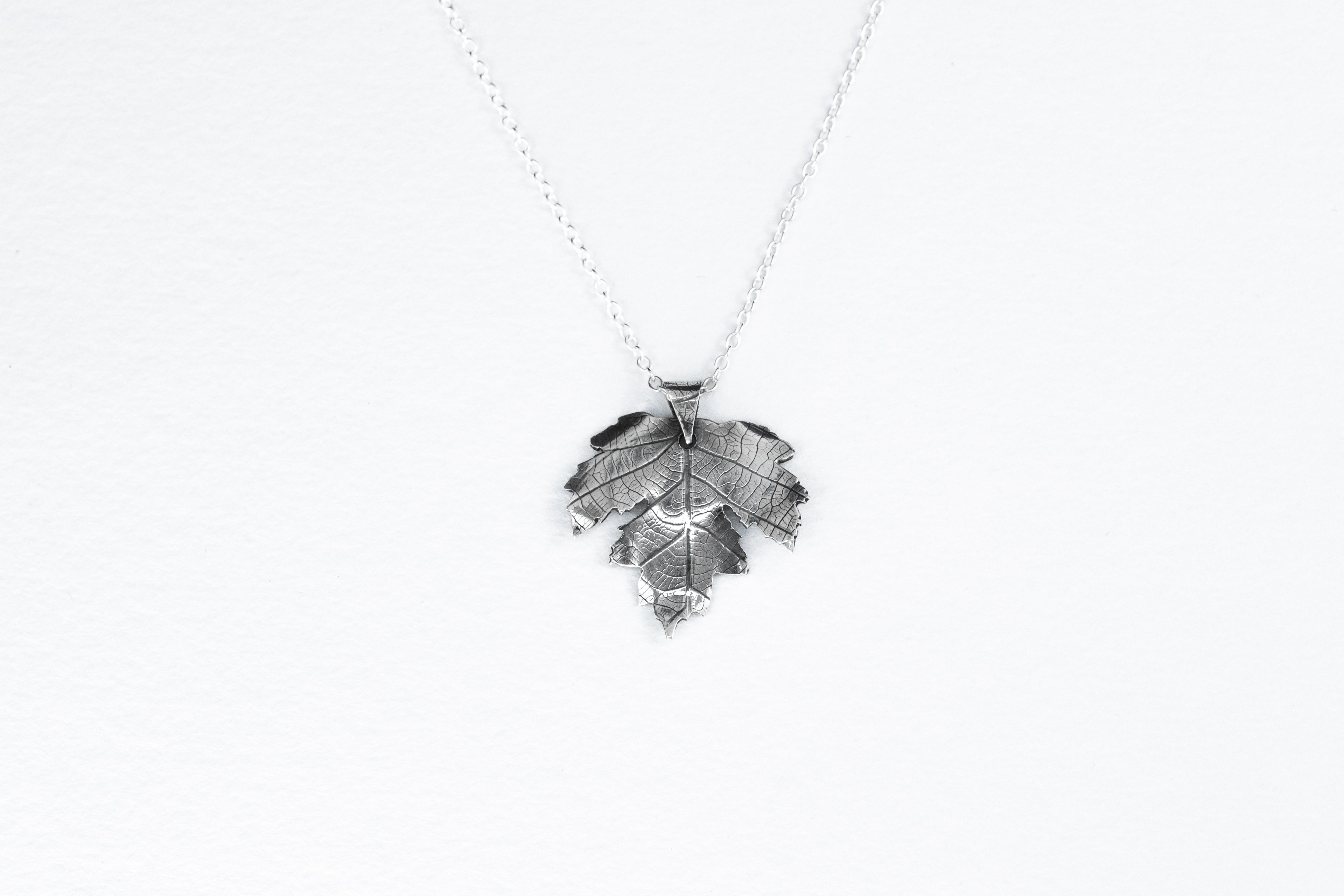 Silver leaf-shaped pendant on a white background