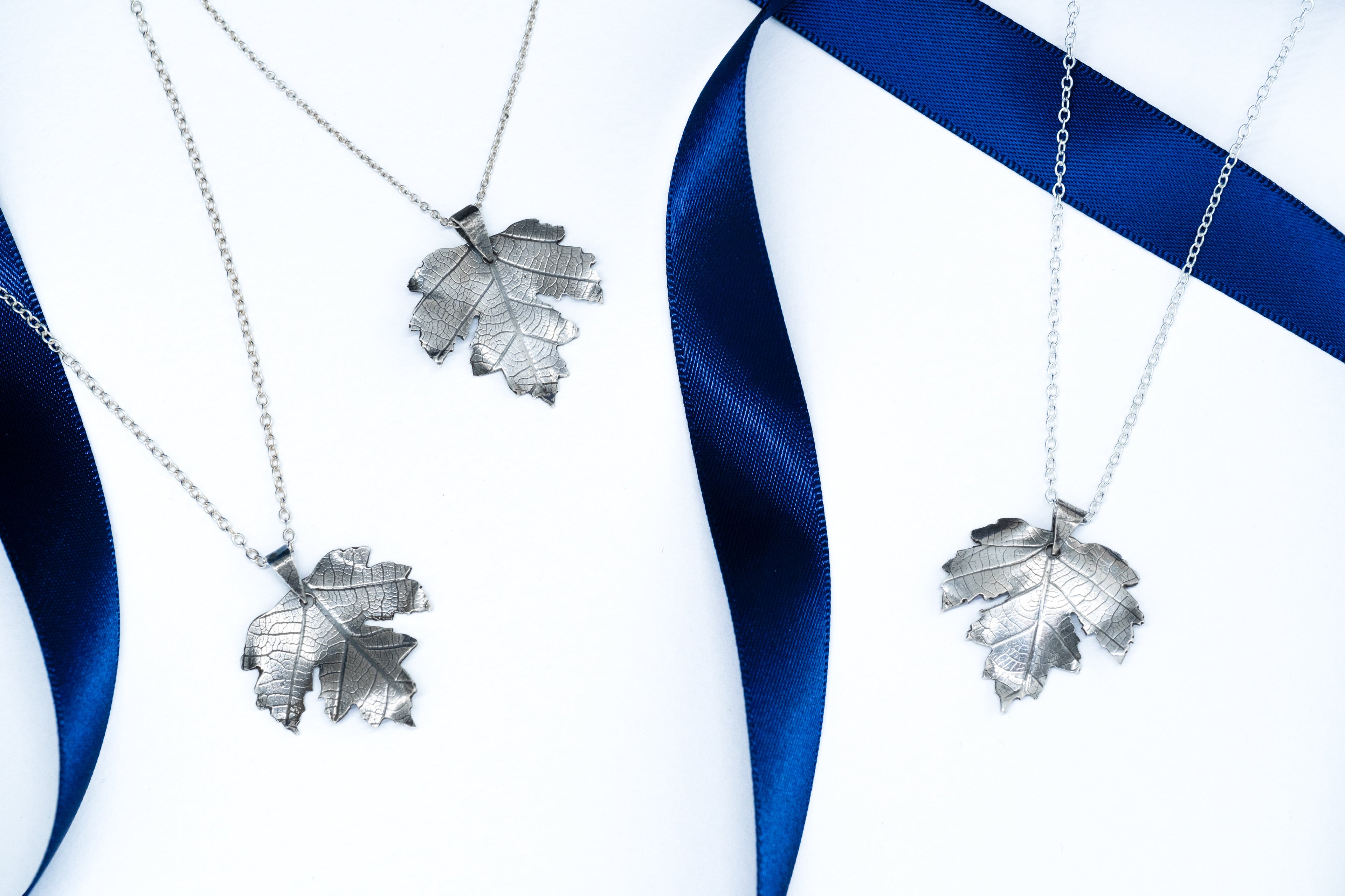 Silver leaf pendants on blue and white ribbons