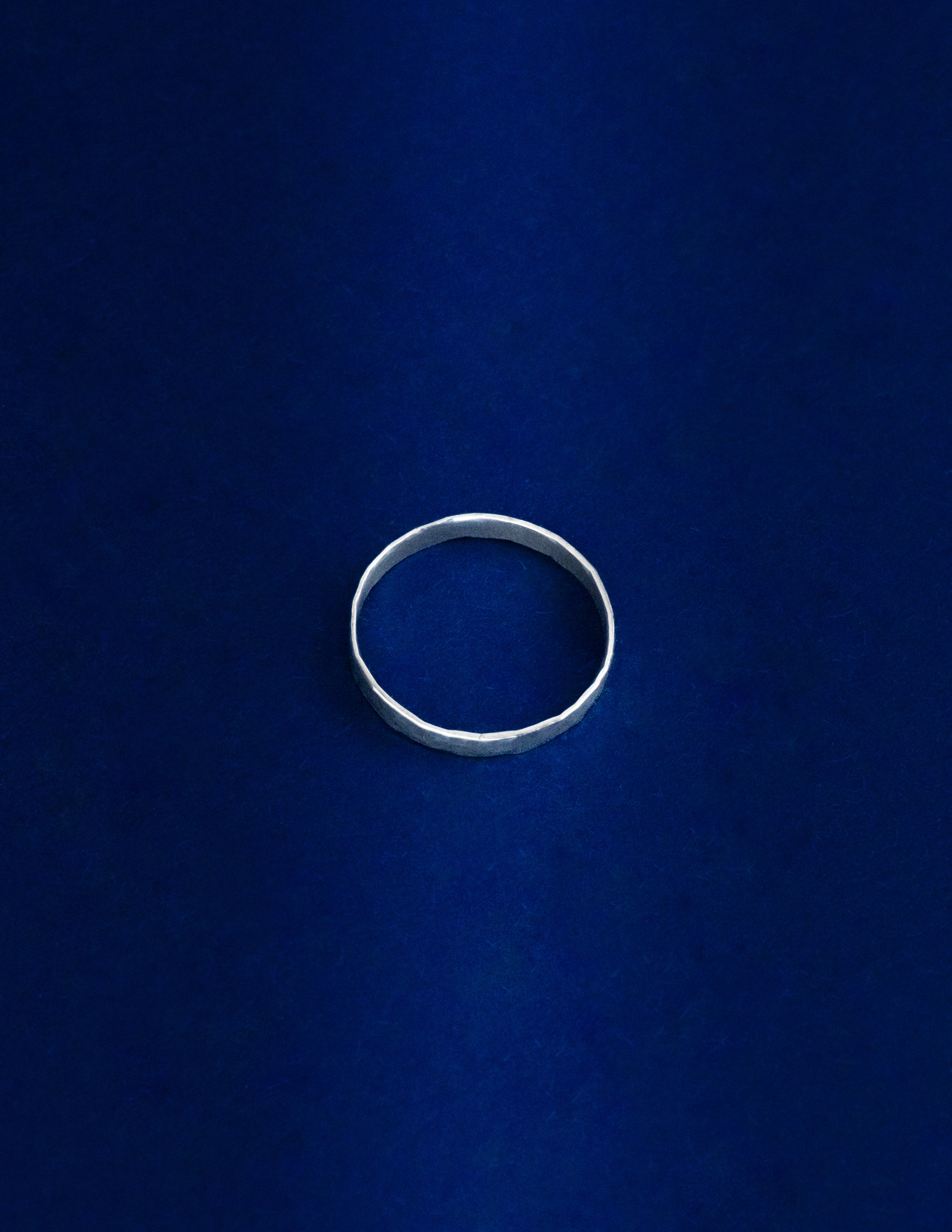 Thicker Ring Lying Flat, Silver ring on a blue background