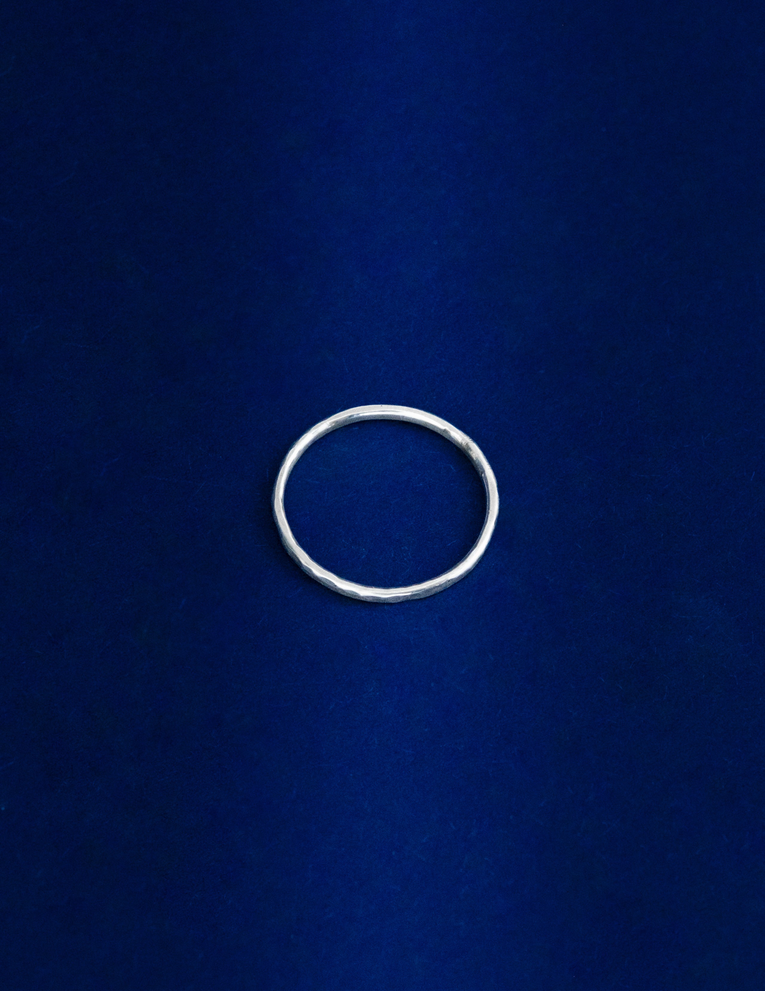 Thin Ring Lying Flat, Silver ring on a blue background