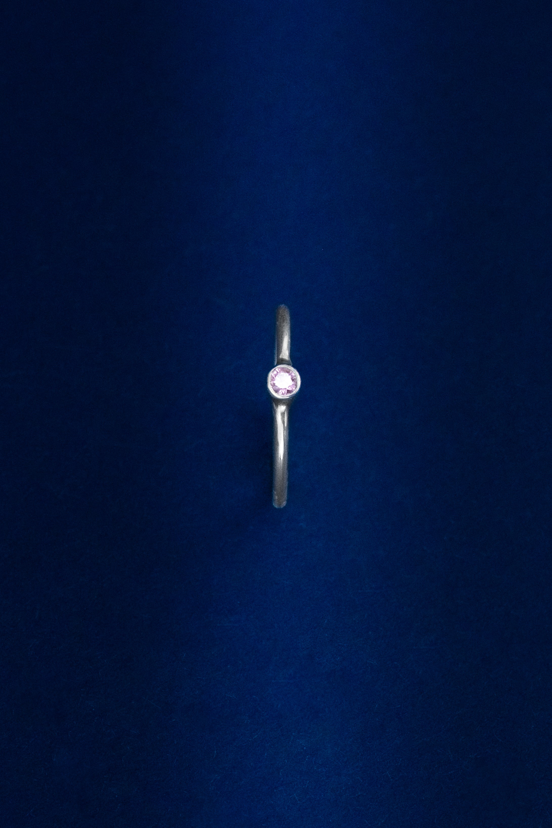 Silver ring with a red gemstone on a dark blue background