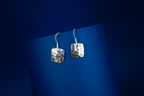 Pair of silver earrings on a blue background