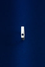 Silver ring with a dark gemstone on a blue background