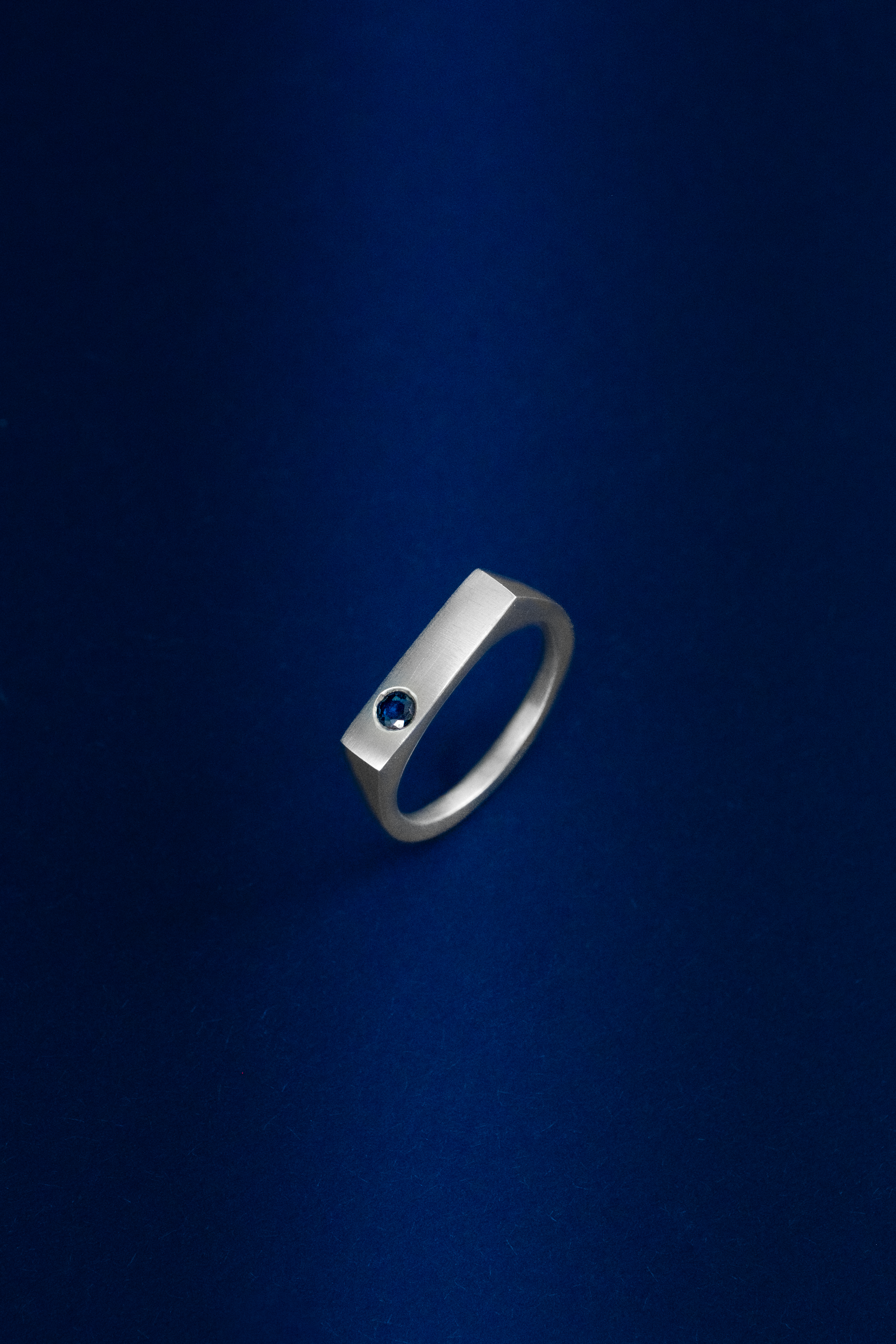 Silver ring with a blue gemstone on a blue background
