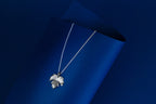 Silver necklace with a leaf pendant on a blue background