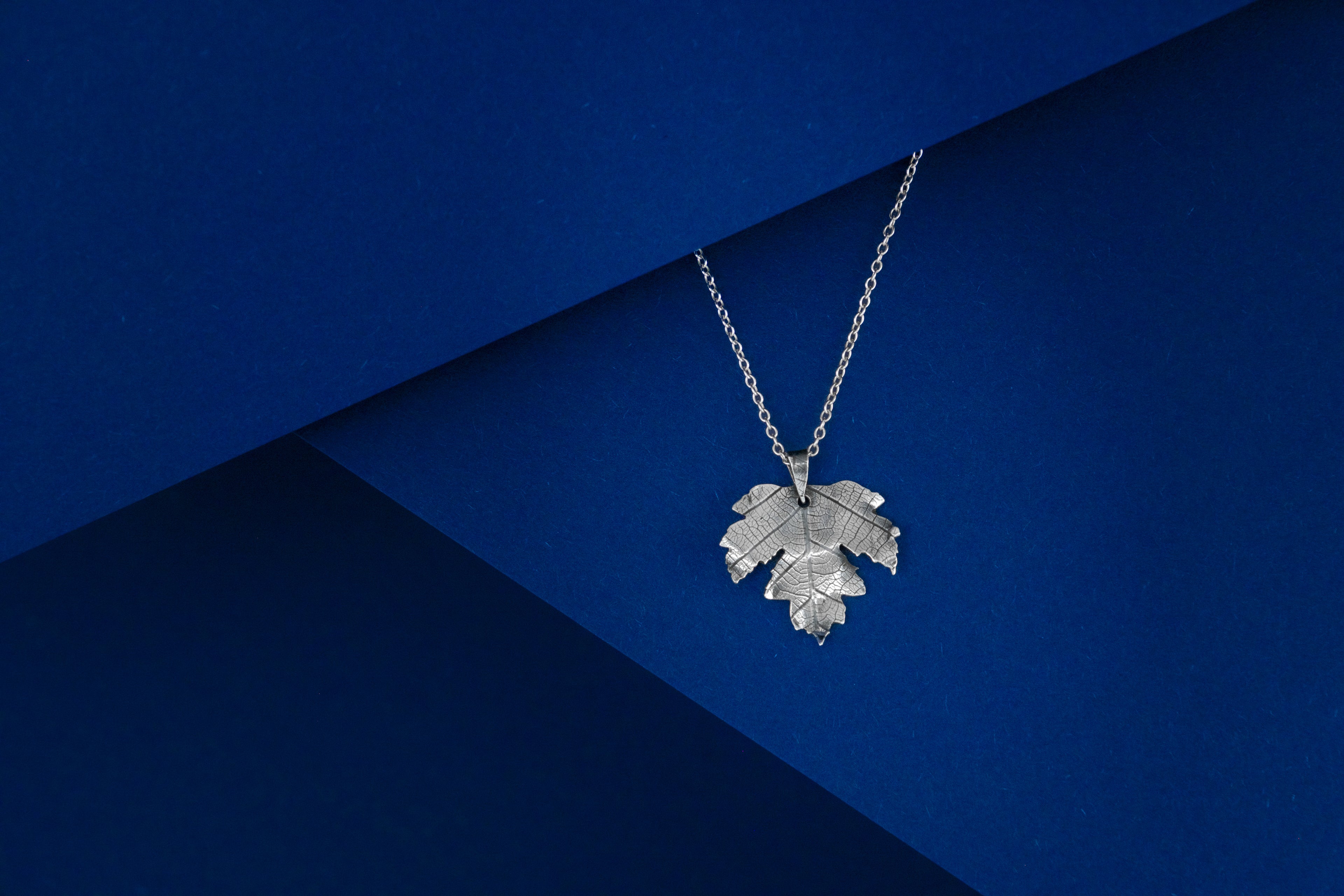 Silver leaf-shaped pendant on a blue background