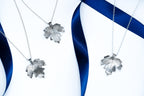 Silver leaf pendants on blue and white ribbons