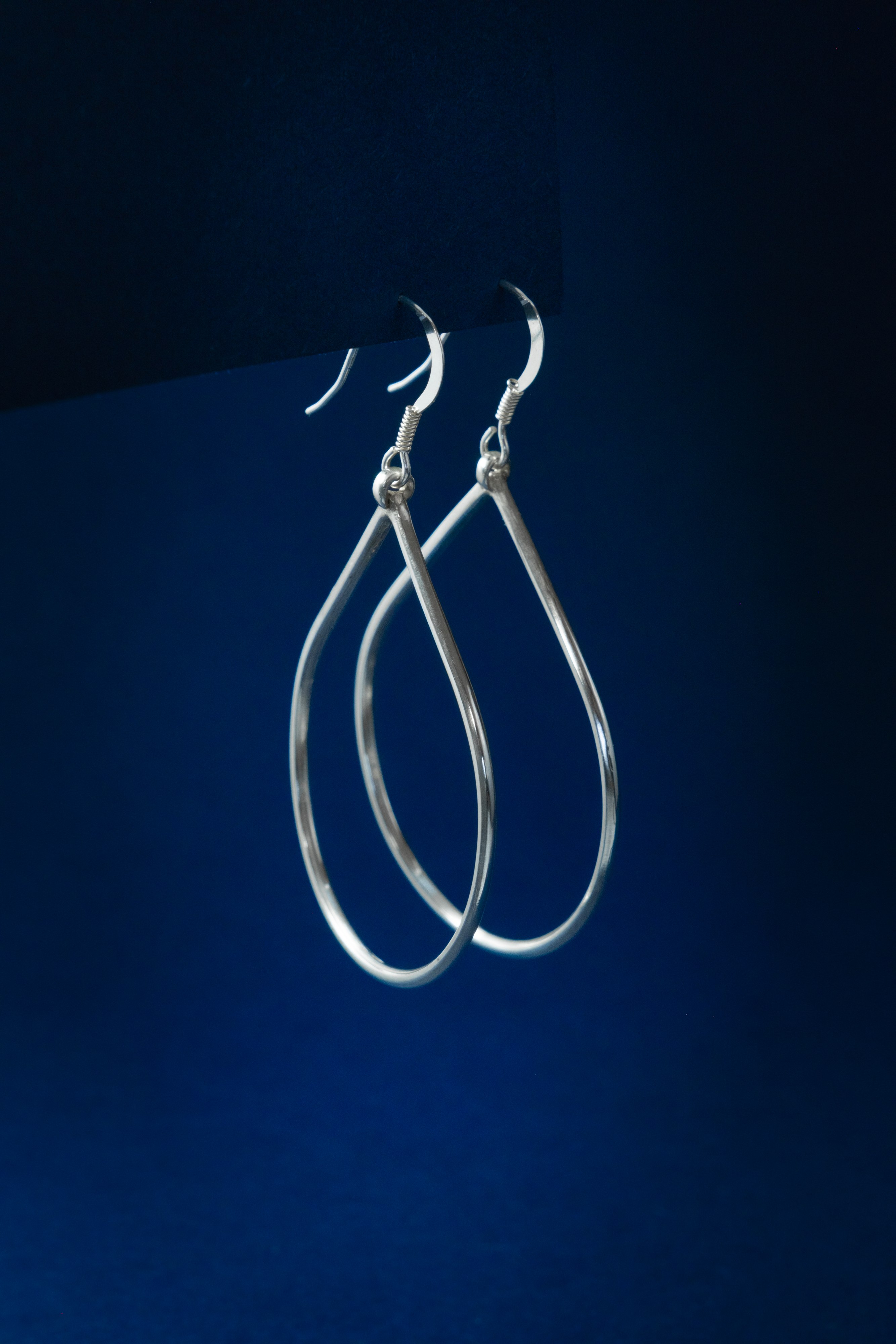 Silver hoop earrings on a dark blue background