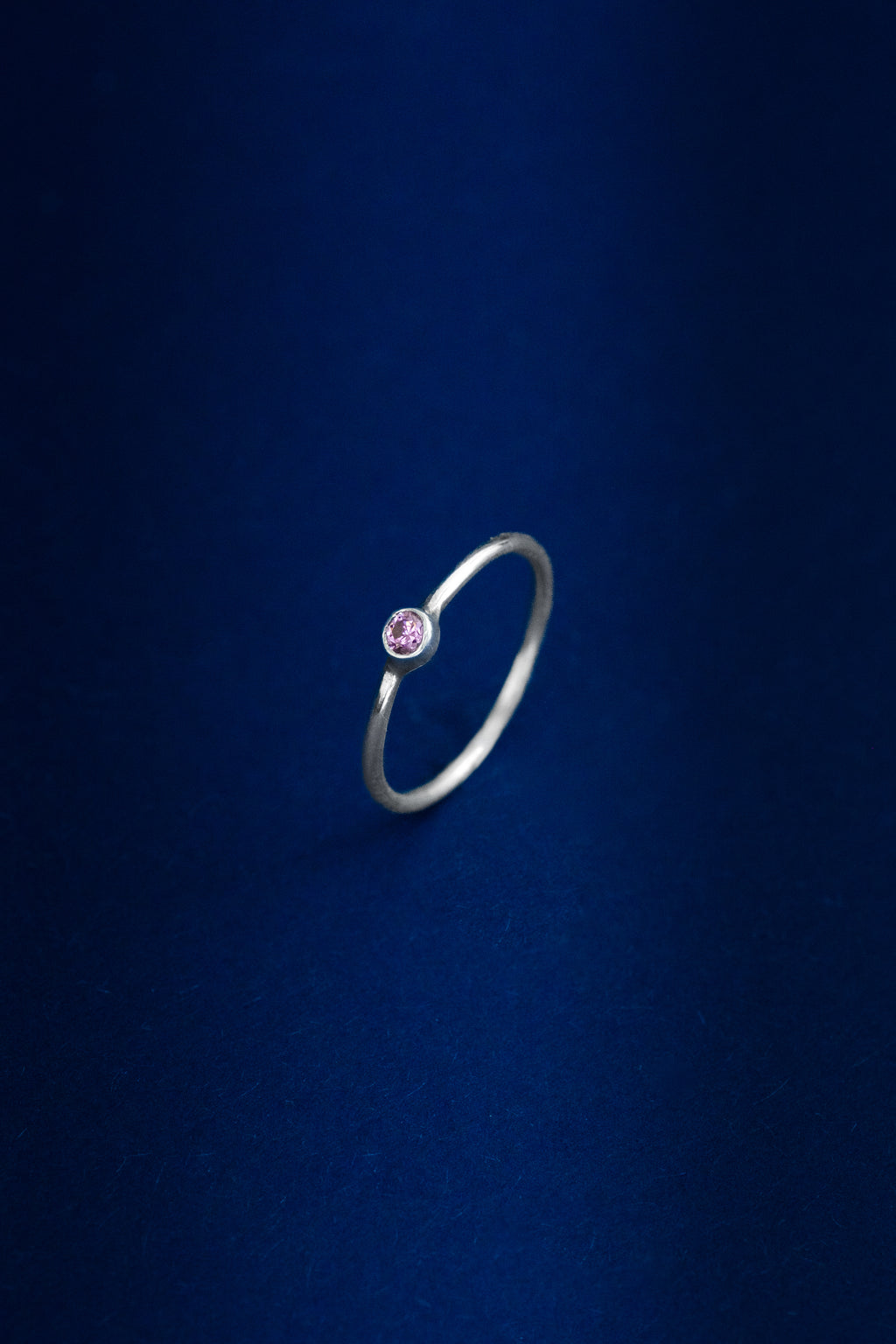Silver ring with a pink gemstone on a dark blue background