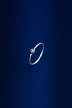 Silver ring with a pink gemstone on a dark blue background