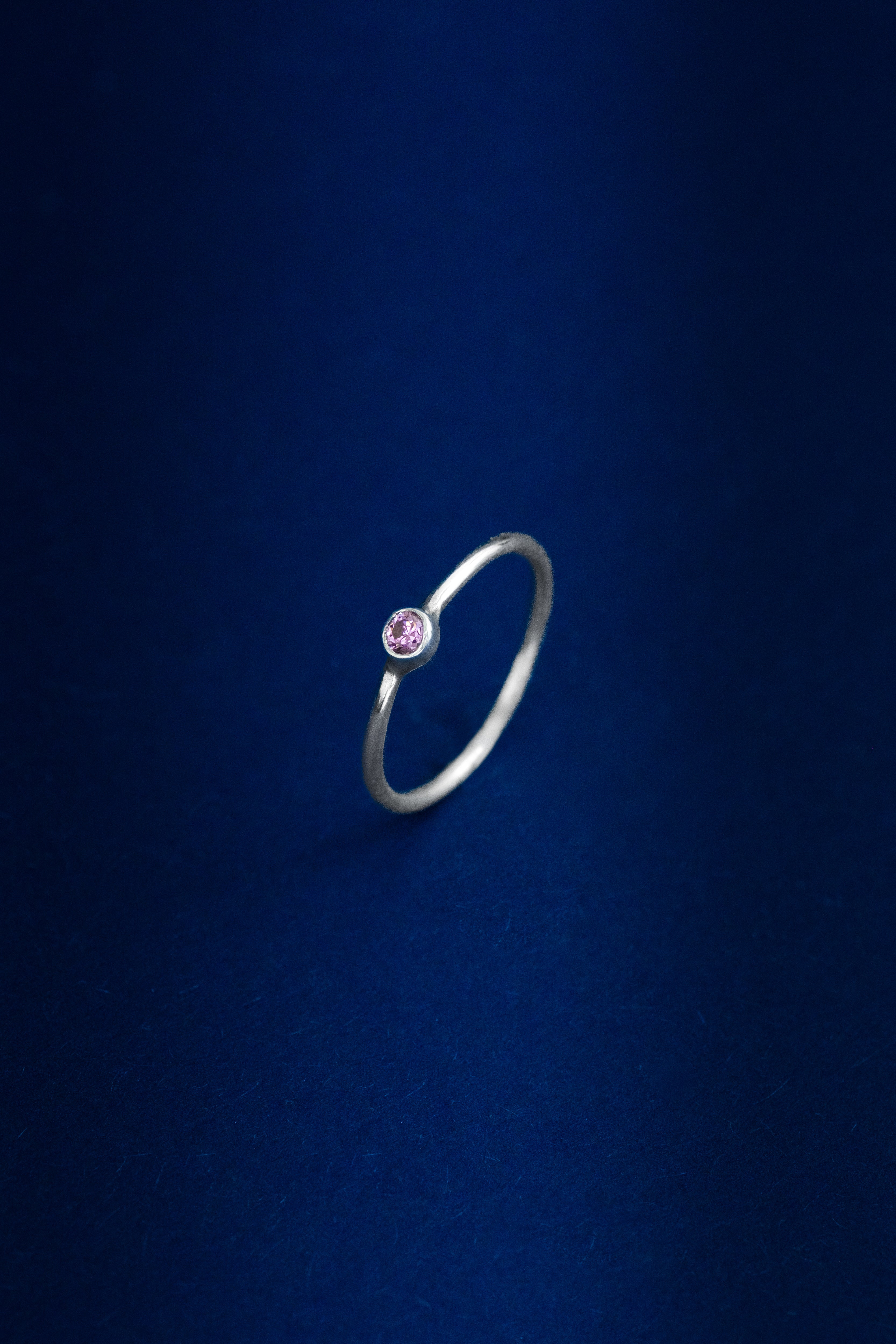 Silver ring with a pink gemstone on a dark blue background