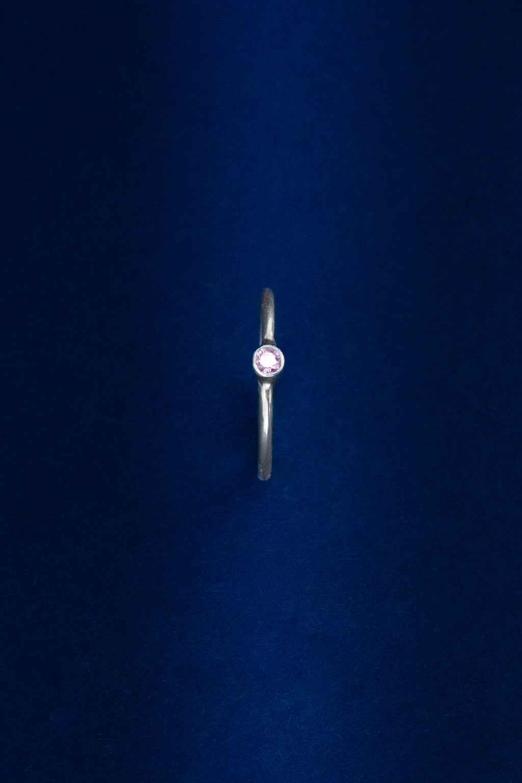 Silver ring with a red gemstone on a dark blue background