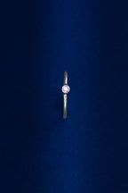 Silver ring with a red gemstone on a dark blue background